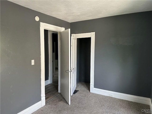 unfurnished bedroom featuring a textured ceiling and dark carpet