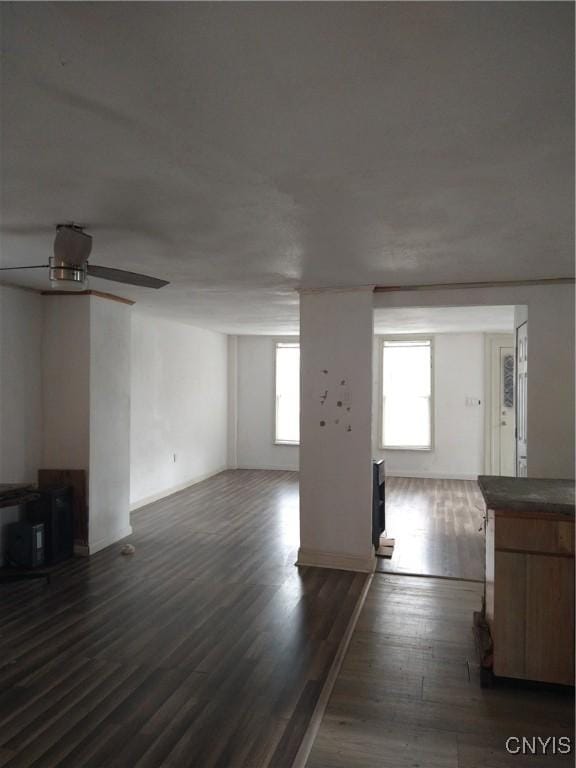 unfurnished living room featuring ceiling fan and dark hardwood / wood-style floors