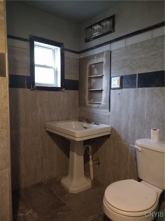 bathroom featuring toilet and tile walls