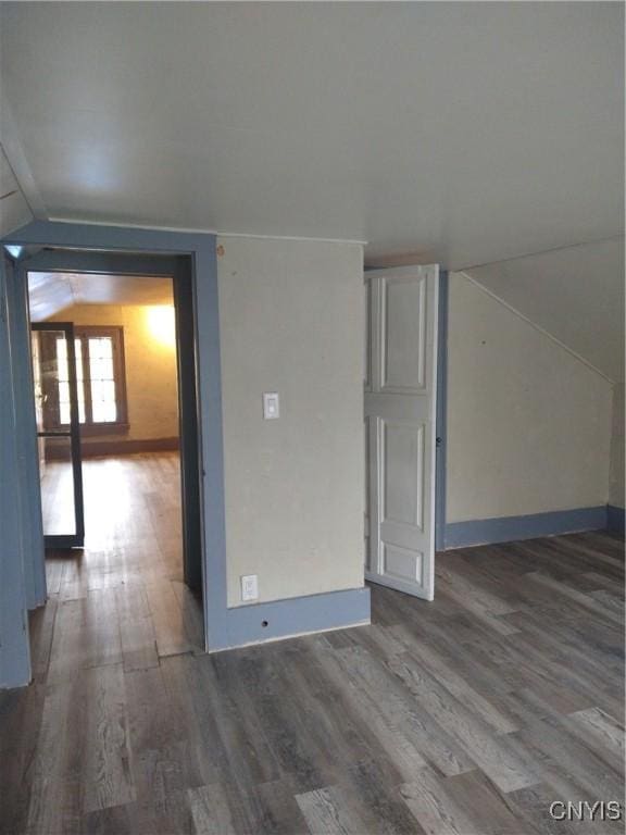 unfurnished room featuring wood-type flooring and vaulted ceiling