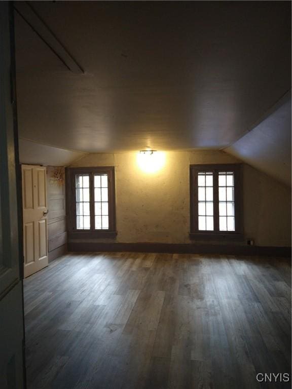 bonus room with a wealth of natural light, dark wood-type flooring, and vaulted ceiling