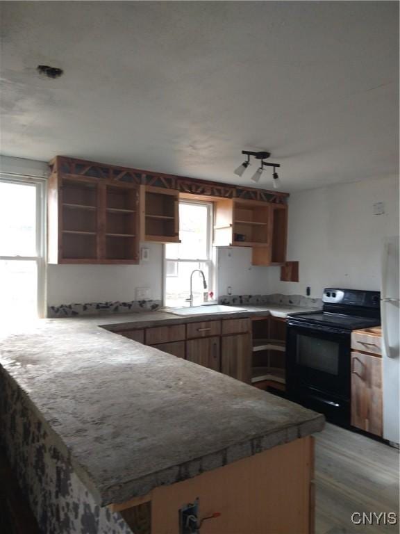 kitchen with kitchen peninsula, refrigerator, sink, light hardwood / wood-style floors, and black / electric stove