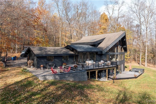 rear view of house featuring a lawn, an outdoor living space, a deck, and a patio