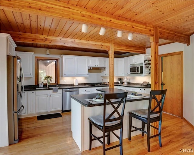 kitchen featuring beam ceiling, white cabinets, stainless steel appliances, and light wood-type flooring