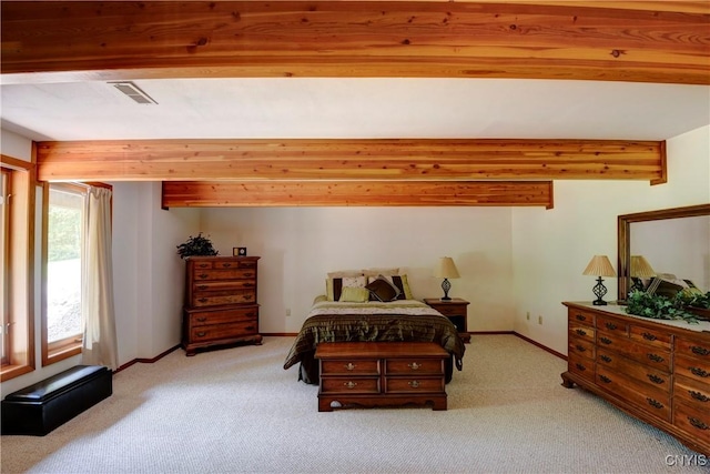 bedroom with beam ceiling and light colored carpet