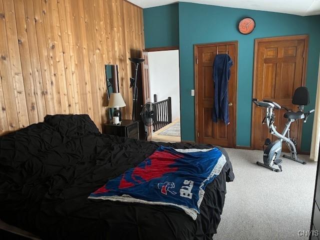 carpeted bedroom featuring lofted ceiling and wooden walls