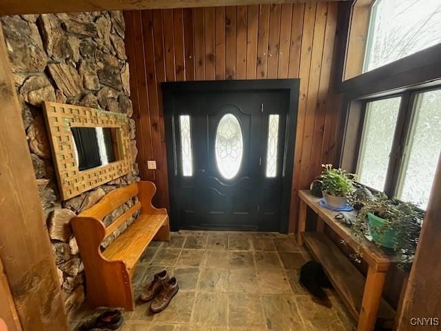 foyer with a wealth of natural light and wood walls