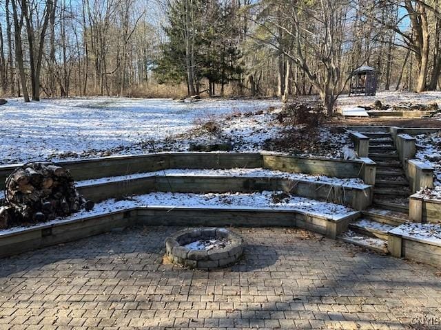 snowy yard with a fire pit and a patio area