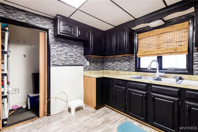 kitchen with tasteful backsplash, light hardwood / wood-style floors, sink, and a drop ceiling