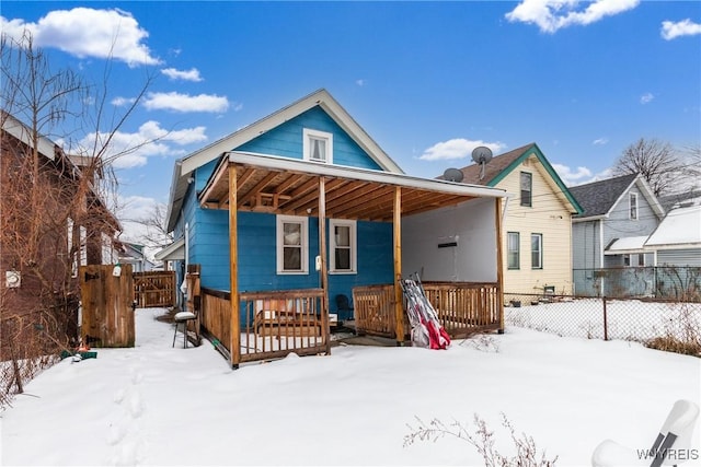 snow covered back of property with a porch