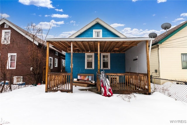 snow covered rear of property with covered porch