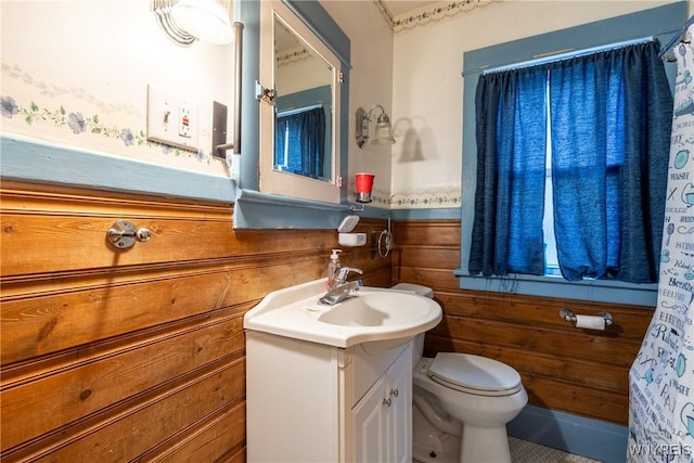 bathroom with vanity, wooden walls, and toilet