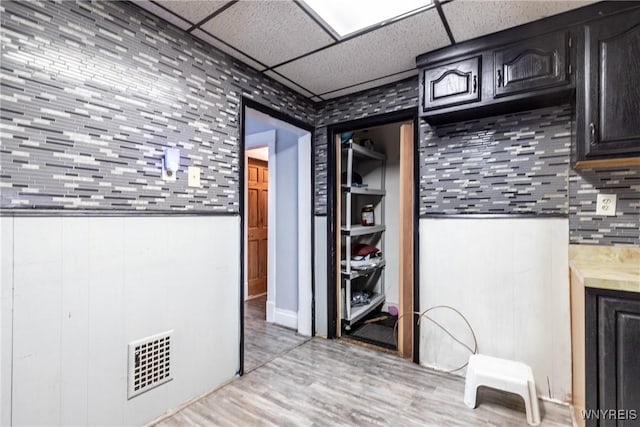 kitchen featuring backsplash, a paneled ceiling, and light wood-type flooring