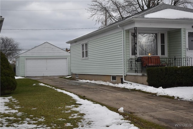 view of snowy exterior featuring an outbuilding and a garage