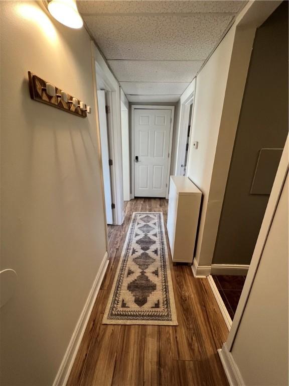 hall with dark hardwood / wood-style flooring and a drop ceiling