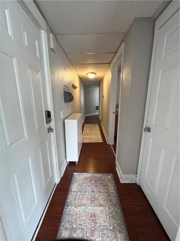 corridor with dark hardwood / wood-style flooring and a drop ceiling