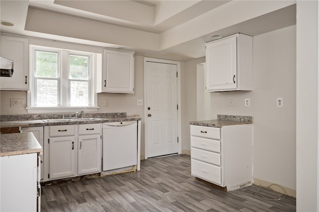 kitchen featuring white dishwasher, white cabinets, a raised ceiling, sink, and hardwood / wood-style flooring