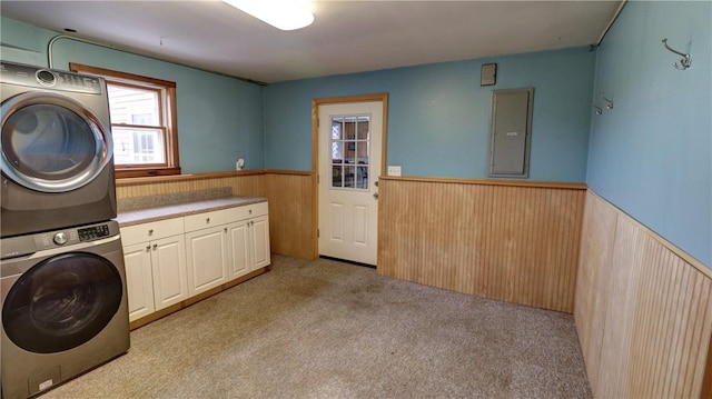 laundry area with cabinets, light colored carpet, stacked washer / dryer, and electric panel