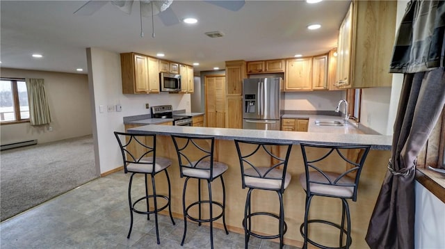 kitchen featuring kitchen peninsula, appliances with stainless steel finishes, a breakfast bar, and sink