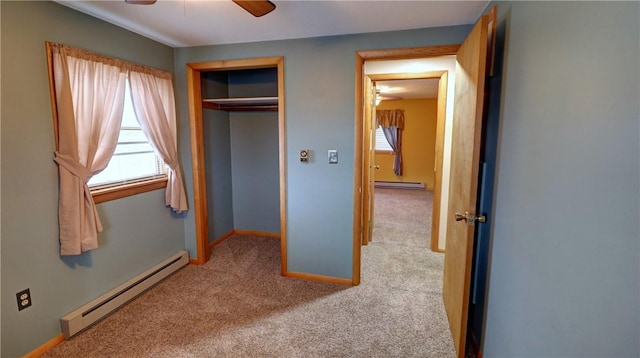 unfurnished bedroom featuring a baseboard radiator, a closet, light colored carpet, and ceiling fan