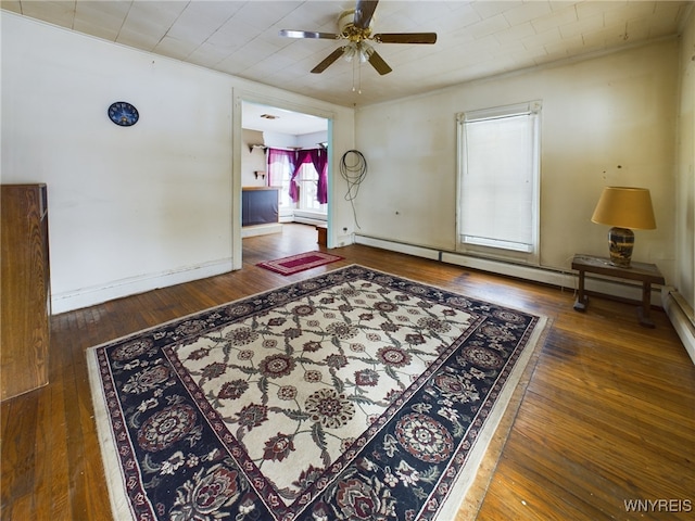 interior space with dark wood-type flooring, a baseboard radiator, and ceiling fan