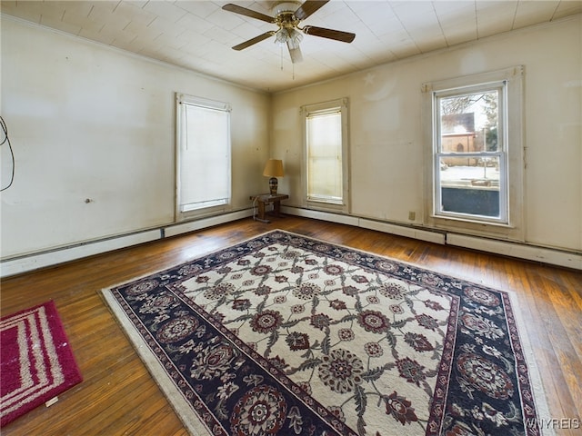 empty room featuring dark wood-type flooring, ceiling fan, and a baseboard heating unit