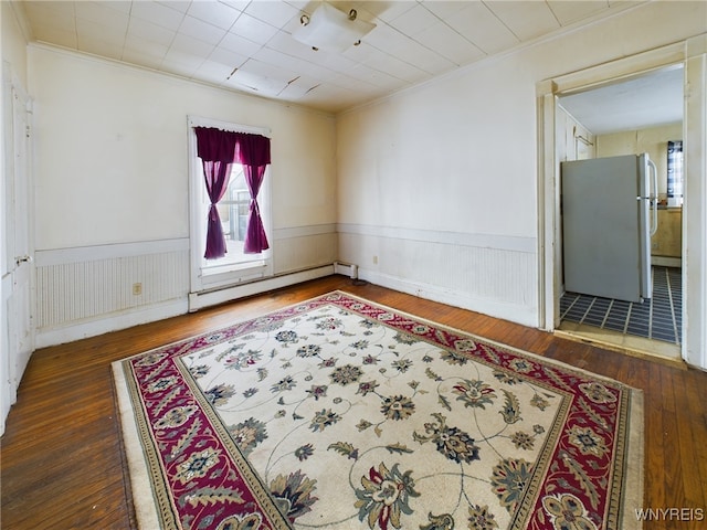 spare room featuring dark wood-type flooring, a baseboard radiator, and ornamental molding