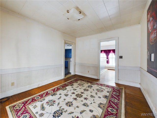 empty room with ornamental molding, dark hardwood / wood-style floors, and a baseboard heating unit