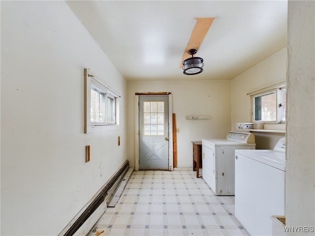 clothes washing area with cabinets, a wealth of natural light, and washer and clothes dryer