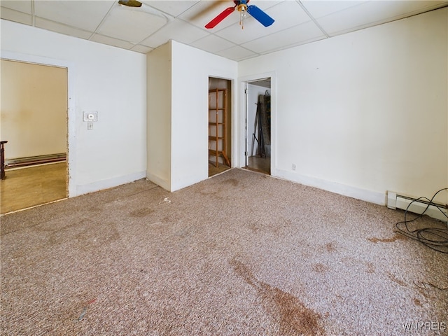 empty room with ceiling fan, a baseboard radiator, carpet, and a drop ceiling