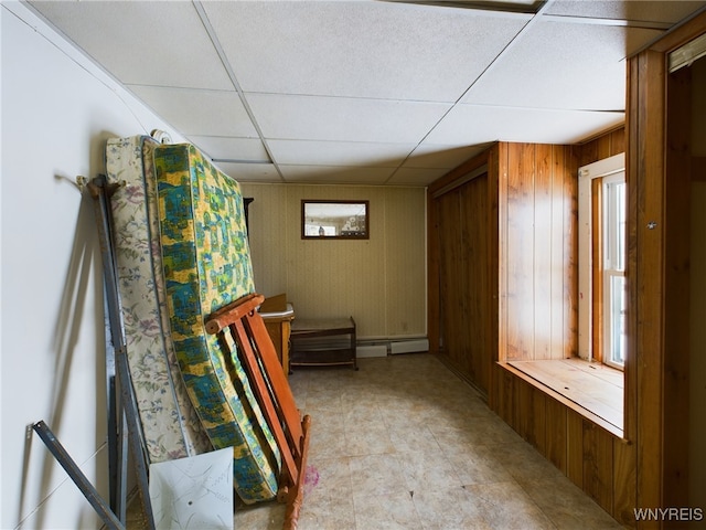 interior space featuring a paneled ceiling and wood walls