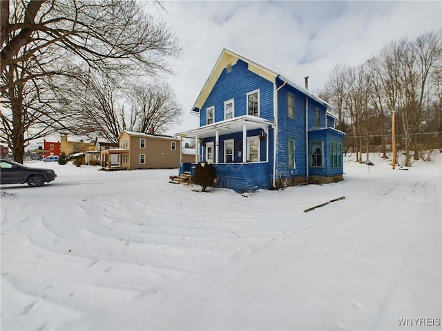 snow covered back of property with a porch