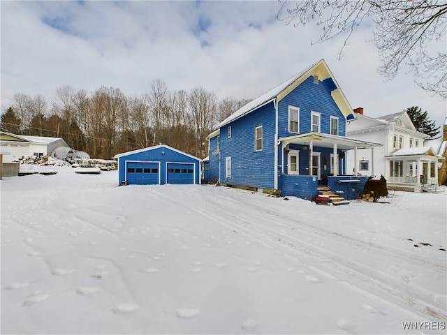 view of snowy exterior with a garage, an outdoor structure, and covered porch