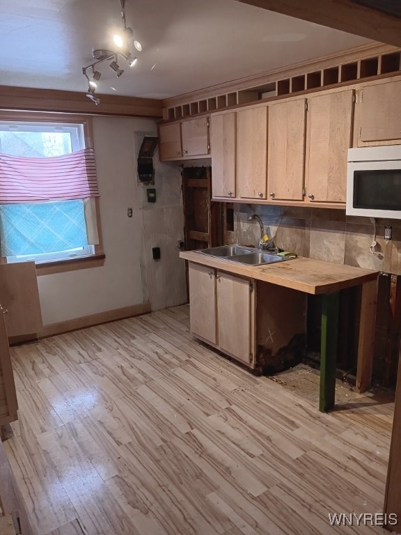 kitchen featuring decorative backsplash, light hardwood / wood-style floors, sink, and light brown cabinetry