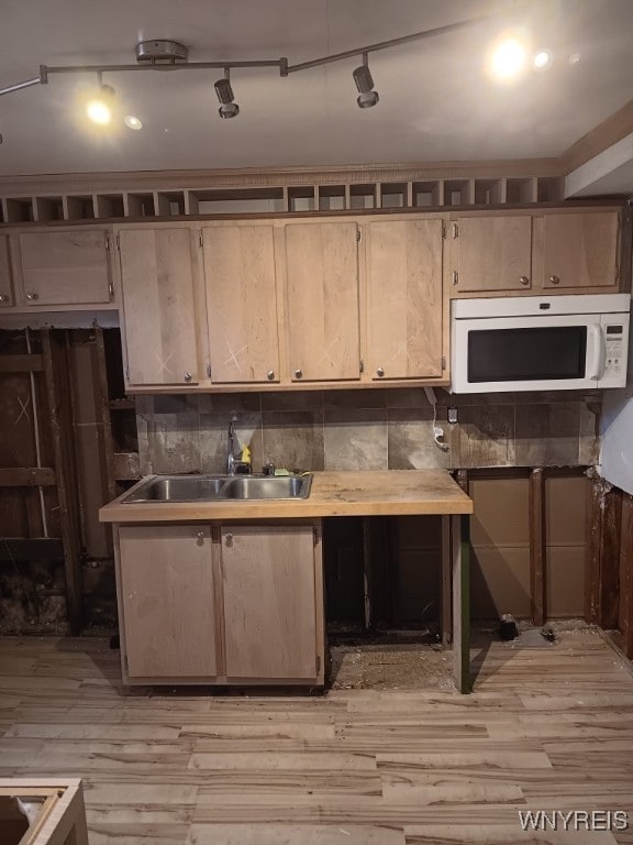 kitchen with backsplash, track lighting, sink, and light hardwood / wood-style flooring