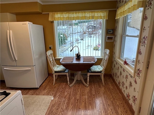 dining room featuring a healthy amount of sunlight, light hardwood / wood-style floors, and ornamental molding