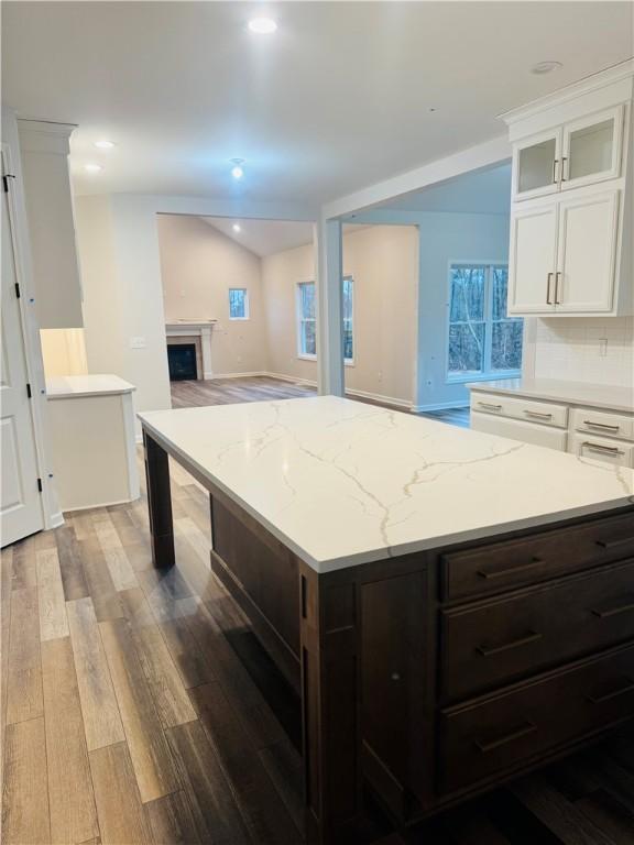 kitchen with white cabinets, vaulted ceiling, decorative backsplash, dark brown cabinetry, and wood-type flooring