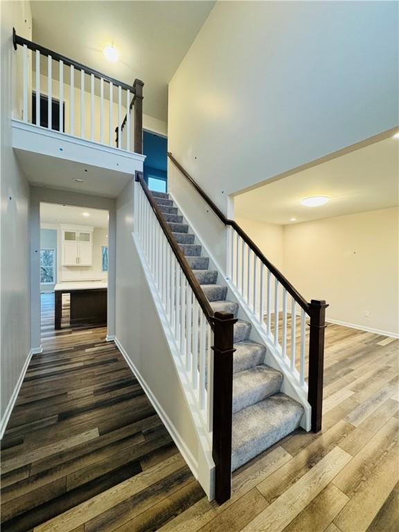 stairs featuring wood-type flooring and a high ceiling