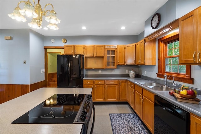 kitchen featuring wooden walls, sink, black appliances, decorative light fixtures, and a chandelier