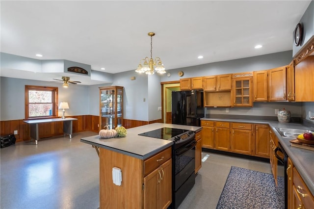 kitchen featuring pendant lighting, wood walls, black appliances, sink, and a kitchen island