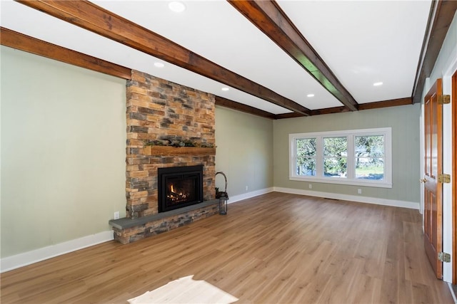 unfurnished living room with beamed ceiling, light hardwood / wood-style flooring, and a stone fireplace