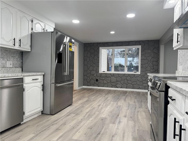 kitchen with white cabinets, light hardwood / wood-style floors, ventilation hood, and stainless steel appliances