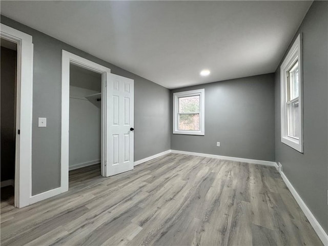 unfurnished bedroom with a walk in closet, light wood-type flooring, and a closet