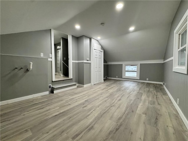 bonus room with light wood-type flooring and vaulted ceiling