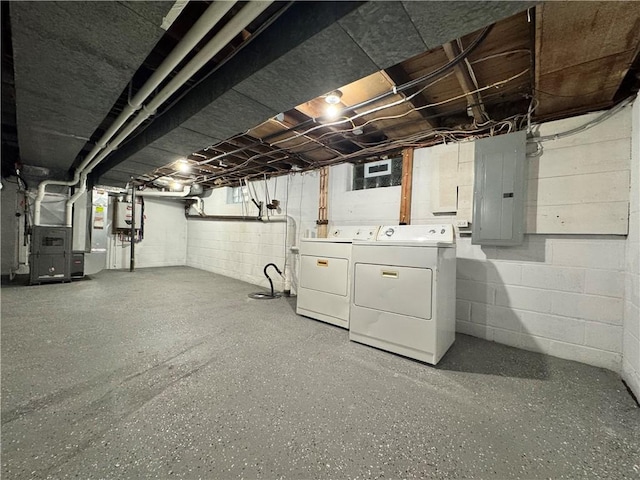 basement featuring electric panel, water heater, heating unit, and washer and dryer