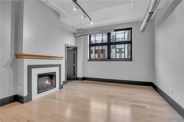 unfurnished living room featuring rail lighting and light wood-type flooring