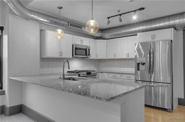 kitchen with white cabinets, light stone countertops, kitchen peninsula, and appliances with stainless steel finishes