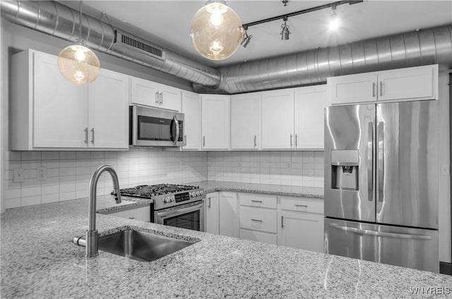 kitchen featuring white cabinets, stainless steel appliances, hanging light fixtures, and sink