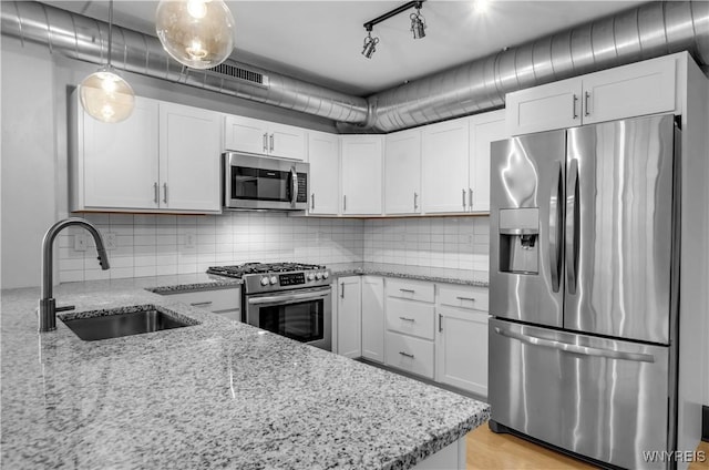 kitchen with light stone counters, stainless steel appliances, sink, pendant lighting, and white cabinets