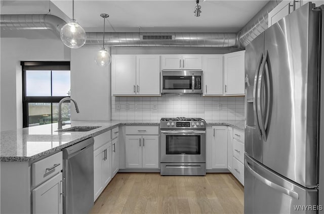 kitchen with decorative light fixtures, stainless steel appliances, white cabinetry, and sink